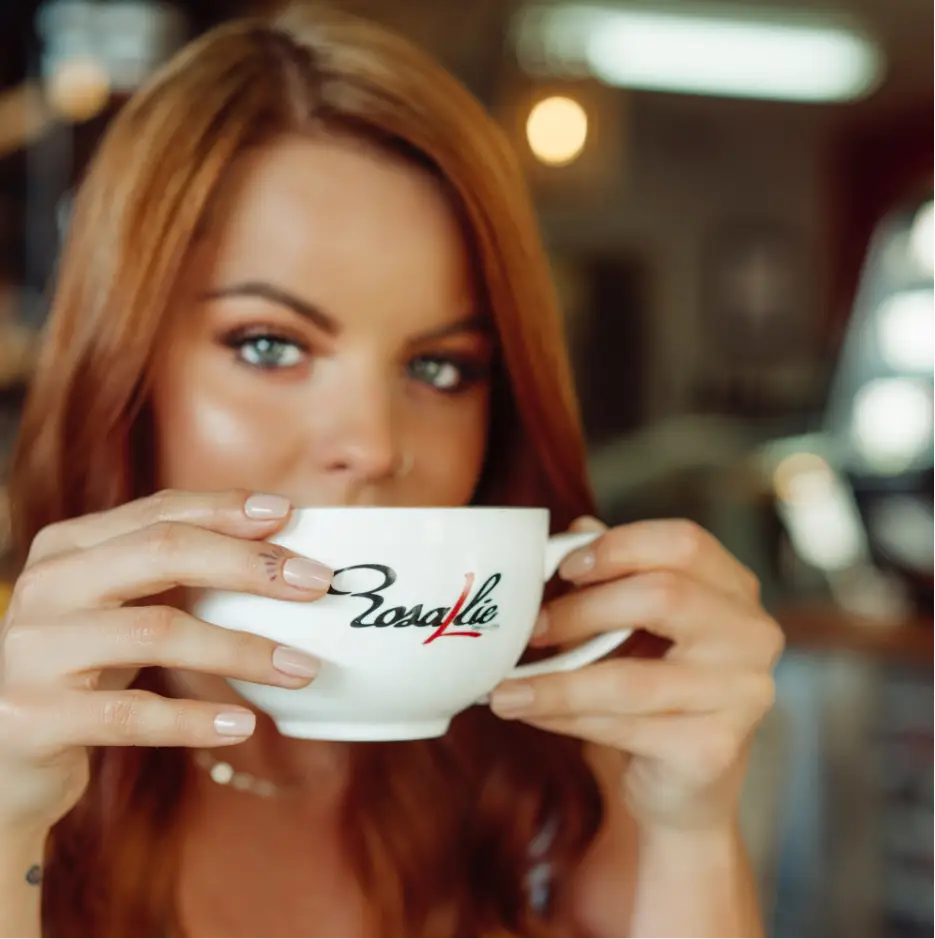 Rosallie Café coffee cup on an outdoor patio table with fresh flowers, creating a warm and inviting morning café atmosphere.