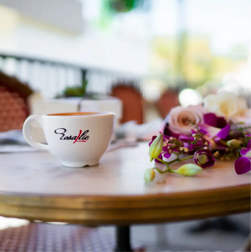Rosallie café coffee cup on an outdoor table decorated with fresh flowers, capturing a cozy and elegant café ambiance.