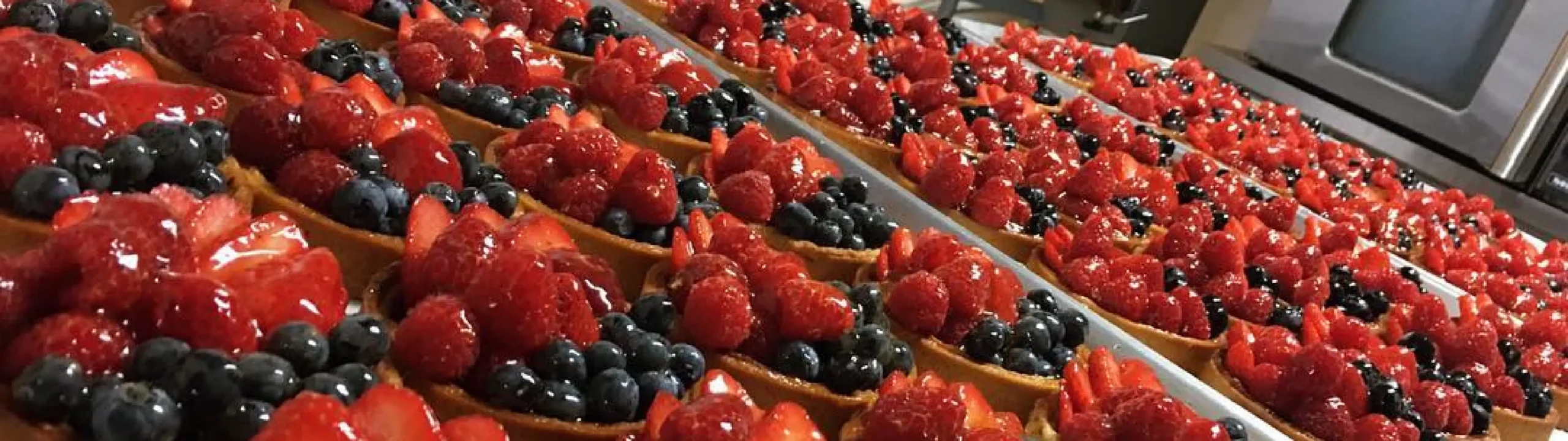 Rows of fresh berry tarts with strawberries, raspberries, and blueberries at Rosallie French Bakery in Las Vegas