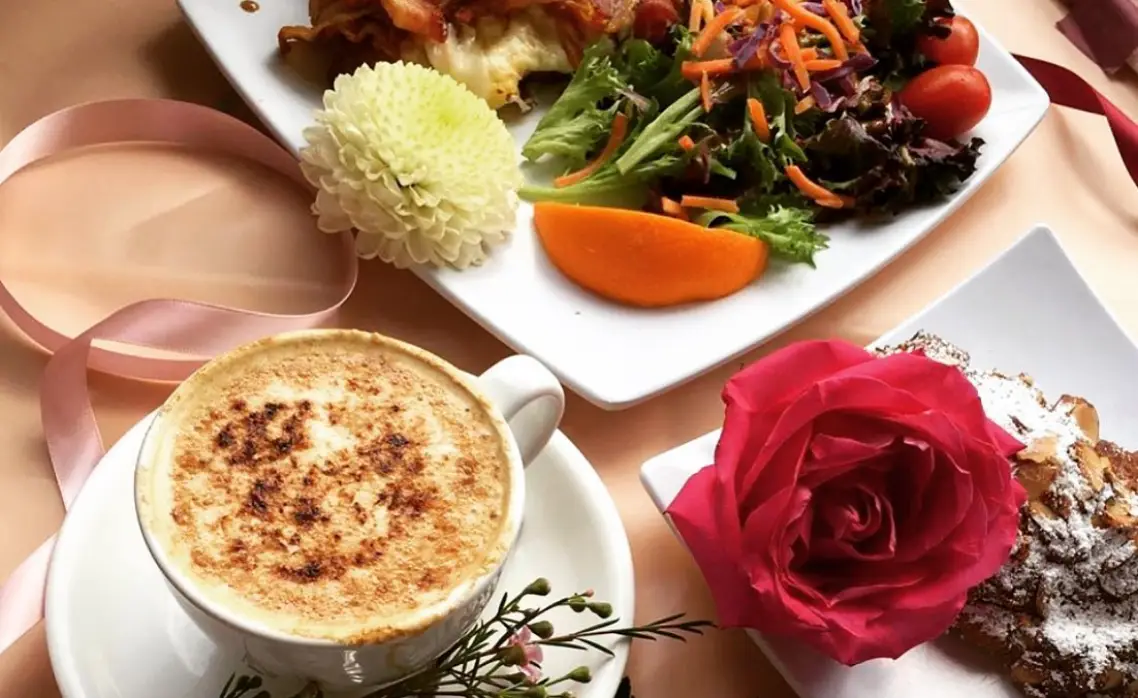 Cappuccino, fresh salad, and French pastry served at Rosallie French Café brunch table with rose decor